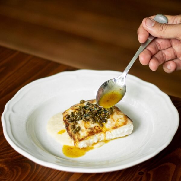Sauce spooned over a fish fillet topped with capers and olive crumb