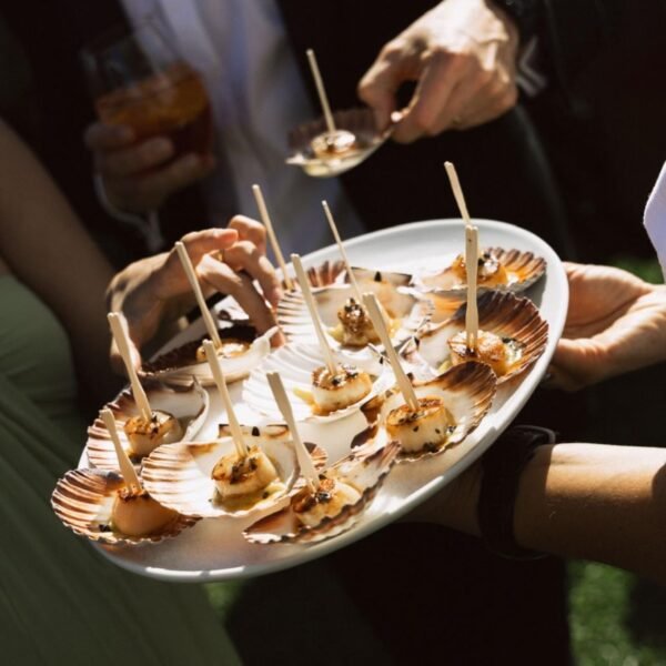 Guests taking scallop canapés from a serving platter